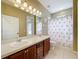 Bathroom with a double sink vanity, flamingo-themed shower curtain, and ample lighting, offering functionality and style at 13546 Biscayne Grove Ln, Grand Island, FL 32735