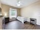 Bedroom showcasing wood-look floors, two windows with curtains, and a quaint white iron bed, radiating charm and tranquility at 13546 Biscayne Grove Ln, Grand Island, FL 32735