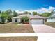 Inviting single-story home featuring a paved driveway, landscaping, and a two-car garage, creating curb appeal at 13546 Biscayne Grove Ln, Grand Island, FL 32735