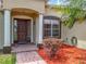 Close-up of the front entrance featuring a dark wood door, decorative pillars, and colorful landscaping details at 13546 Biscayne Grove Ln, Grand Island, FL 32735