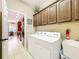 Laundry room with full size washer and dryer and cherry cabinets above at 13546 Biscayne Grove Ln, Grand Island, FL 32735