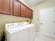 Laundry room with full size washer and dryer and cherry cabinets above at 13546 Biscayne Grove Ln, Grand Island, FL 32735