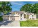 Charming single-story home boasts a manicured lawn, three-car garage, and tasteful landscaping at 14421 Pine Cone Trl, Clermont, FL 34711