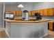 Open kitchen with wood cabinets, stainless steel appliances, and breakfast bar with tile floor at 14421 Pine Cone Trl, Clermont, FL 34711