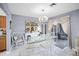Elegant dining area with a glass table, white chairs, decorative chandelier, and sliding glass door to a patio at 16 Pine Run, Haines City, FL 33844