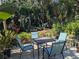 Inviting back patio features a table with seating surrounded by lush greenery and tropical plants at 16730 Beauclaire Ct, Tavares, FL 32778