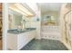 Bright bathroom with a double sink vanity, walk-in closet, a soaking tub, and unique tile flooring at 16730 Beauclaire Ct, Tavares, FL 32778