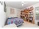 Comfortable bedroom with ceiling fan, large bookshelf, and bright window at 16730 Beauclaire Ct, Tavares, FL 32778