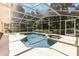 Sparkling pool and hot tub in screened enclosure, surrounded by lush greenery at 16730 Beauclaire Ct, Tavares, FL 32778