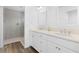 Well-lit bathroom featuring double sinks, white cabinets, and tiled walk-in shower at 1674 Cadorette Dr, The Villages, FL 34762