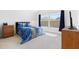 Comfortable bedroom with large window, blue accents, and carpet flooring at 1674 Cadorette Dr, The Villages, FL 34762