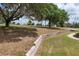 Expansive backyard with mature trees and a retaining wall bordering a scenic landscape, perfect for outdoor enjoyment at 17728 Palm View Cir, Mount Dora, FL 32757