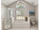 Bright bathroom features a soaking tub, glass shower, and large window for natural light at 17728 Palm View Cir, Mount Dora, FL 32757