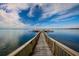 Picturesque wooden dock extending into a tranquil lake, under a sunny sky with scattered clouds at 17728 Palm View Cir, Mount Dora, FL 32757
