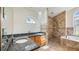 Granite vanity top next to a walk-in shower and garden tub with a large sunny window in the bathroom at 17825 Whisperwind Dr, Clermont, FL 34715