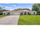 Beautiful single-story home featuring a well-manicured lawn, red double door entrance, and attached two car garage at 17825 Whisperwind Dr, Clermont, FL 34715