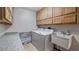 Functional laundry area with overhead storage, modern washer and dryer, and a practical wash sink at 17825 Whisperwind Dr, Clermont, FL 34715