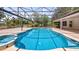 Enclosed pool area featuring a pristine blue swimming pool and spa, surrounded by lush landscaping at 17825 Whisperwind Dr, Clermont, FL 34715