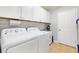 Bright laundry room with modern white appliances, tile flooring and built in cabinets at 2120 Callaway Dr, The Villages, FL 32162