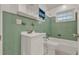 Bathroom with green tile, white sink, toilet, and bathtub at 2209 Hutchinson Ave, Leesburg, FL 34748