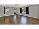 Well-lit living room featuring dark hardwood floors, freshly painted walls, and two large windows at 2209 Hutchinson Ave, Leesburg, FL 34748