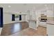 This open floorplan features a kitchen with white cabinets and a living room with dark flooring at 2209 Hutchinson Ave, Leesburg, FL 34748