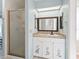 Bathroom with white cabinets, stone countertops, walk-in shower, and a view to the laundry room at 2401 Greenlaw Ct, Leesburg, FL 34788
