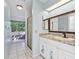 A full bathroom with decorative cabinets and granite counters, plus a shower and open laundry room at 2401 Greenlaw Ct, Leesburg, FL 34788