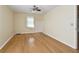 An empty bedroom with hardwood floors, a ceiling fan, and a window with white curtains at 2401 Greenlaw Ct, Leesburg, FL 34788