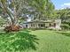 Traditional home with an attached garage, large shade tree and well manicured green lawn at 2401 Greenlaw Ct, Leesburg, FL 34788