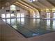 Bright indoor pool featuring high ceilings, many windows, and overhead lighting to create an inviting swimming space at 2401 Greenlaw Ct, Leesburg, FL 34788
