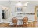Kitchen island with cooktop and seating, white cabinets, and view into breakfast room with red chairs at 2401 Greenlaw Ct, Leesburg, FL 34788