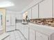 Bright kitchen features white cabinets and appliances, brick-style backsplash, and a stainless steel sink at 2401 Greenlaw Ct, Leesburg, FL 34788