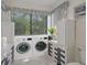 A bright laundry room featuring modern washer and dryer units, bright natural light, and built-in cabinetry at 2401 Greenlaw Ct, Leesburg, FL 34788