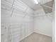 Walk-in closet equipped with ample shelving and storage space, plus neutral carpet flooring at 2401 Greenlaw Ct, Leesburg, FL 34788