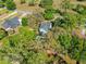 Overhead view shows a charming light blue house with a heart-shaped pool, surrounded by trees in a leafy neighborhood at 25541 Troon Ave, Sorrento, FL 32776