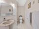 Bathroom features a pedestal sink, toilet, towel rack, and neutral tile flooring at 25541 Troon Ave, Sorrento, FL 32776