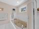 Bathroom with white tile, soaker tub with jets, window, and a shower with glass doors at 25541 Troon Ave, Sorrento, FL 32776