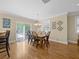 Bright dining room with hardwood floors, a modern chandelier, and sliding doors leading to the outdoor area at 25541 Troon Ave, Sorrento, FL 32776