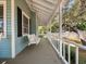 Quaint porch swing on a cozy porch with white railing, blending comfort and charm at 25541 Troon Ave, Sorrento, FL 32776