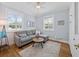 Cozy living room with natural light, hardwood floors, a comfortable couch, and a stylish area rug at 25541 Troon Ave, Sorrento, FL 32776
