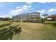 Expansive lawn with manicured landscaping and a screened-in pool area at 2706 Radbourne Way, The Villages, FL 32162