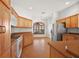 Open-concept kitchen with wood cabinets, tile flooring, and stainless steel appliances, connecting to the dining area at 2706 Radbourne Way, The Villages, FL 32162