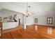 Open-concept living room with hardwood floors, chandelier, columns, and a view into the kitchen at 2706 Radbourne Way, The Villages, FL 32162