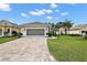 Charming single-story home with a well-maintained lawn and brick driveway under a blue sky at 3584 Tropical Seas Loop, Tavares, FL 32778