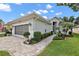 Charming single-story home with a well-maintained lawn and brick driveway under a blue sky at 3584 Tropical Seas Loop, Tavares, FL 32778