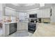 Well-lit kitchen featuring stainless steel appliances, white cabinets, and marbled countertops at 3584 Tropical Seas Loop, Tavares, FL 32778