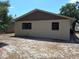 Beige one-story home featuring a fenced-in backyard and brown siding beneath the roof's edge, surrounded by mature trees and sky at 37 N Normandale Ave, Orlando, FL 32835