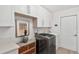 Bright laundry room features white cabinetry, modern washer/dryer, and stylish decor at 39206 Treeline Dr, Lady Lake, FL 32159