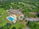 Aerial view featuring the community's clubhouse, pool, tennis courts, golf course, parking area, and lush, mature trees at 39653 Grove Hts, Lady Lake, FL 32159